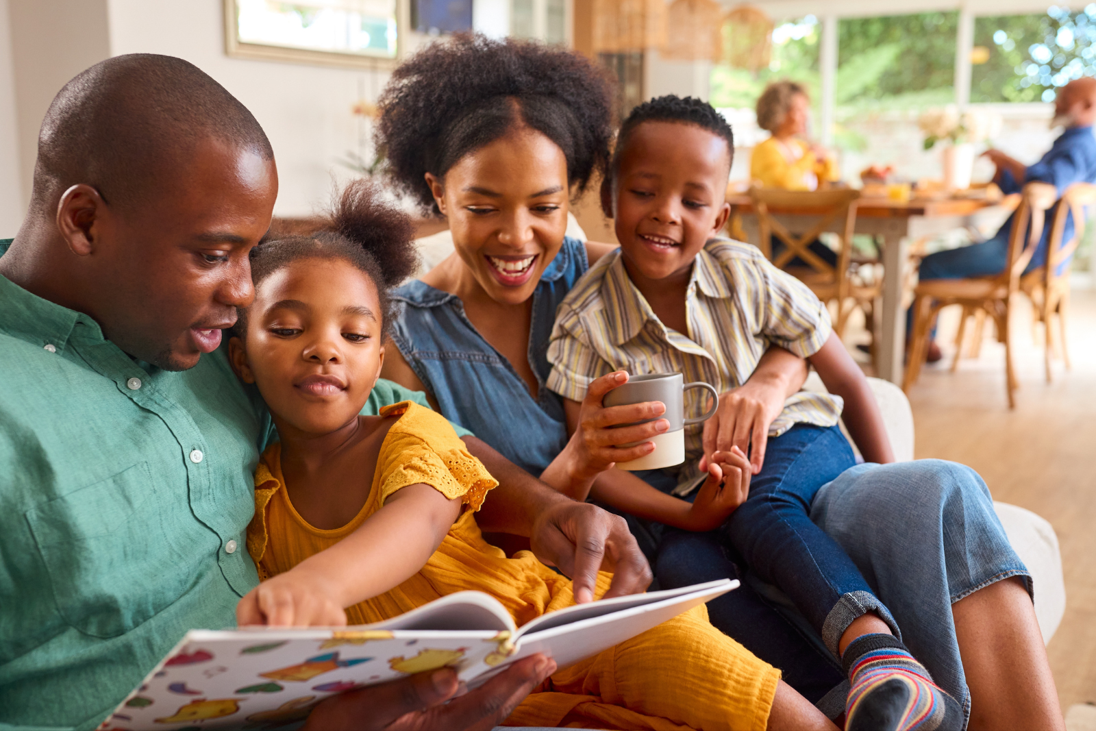 Family reading a book together on the sofa. Kids enjoying storytime.